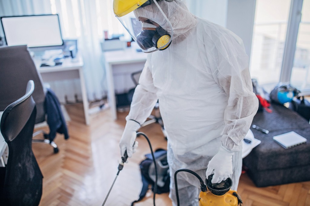 Profissional da ProteLax em equipamento de proteção realizando sanitização